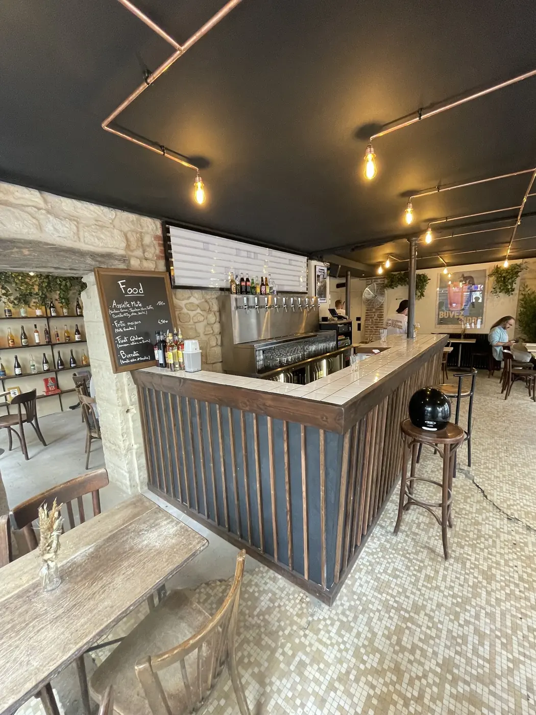 Comptoir et salle d'un restaurant rénové aux Batignolles, plafond noir et cuivre