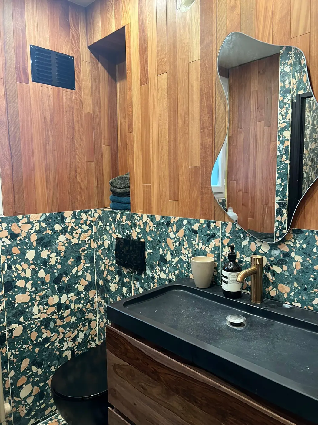 Salle d'eau en terrazzo vert et habillage bois avec vasque noire