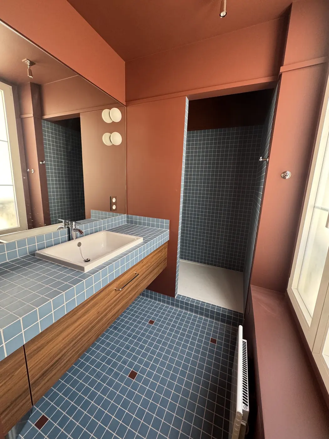 Salle de bains avec plan vasque en mosaïque bleue, bois et murs terracotta à Paris 7e