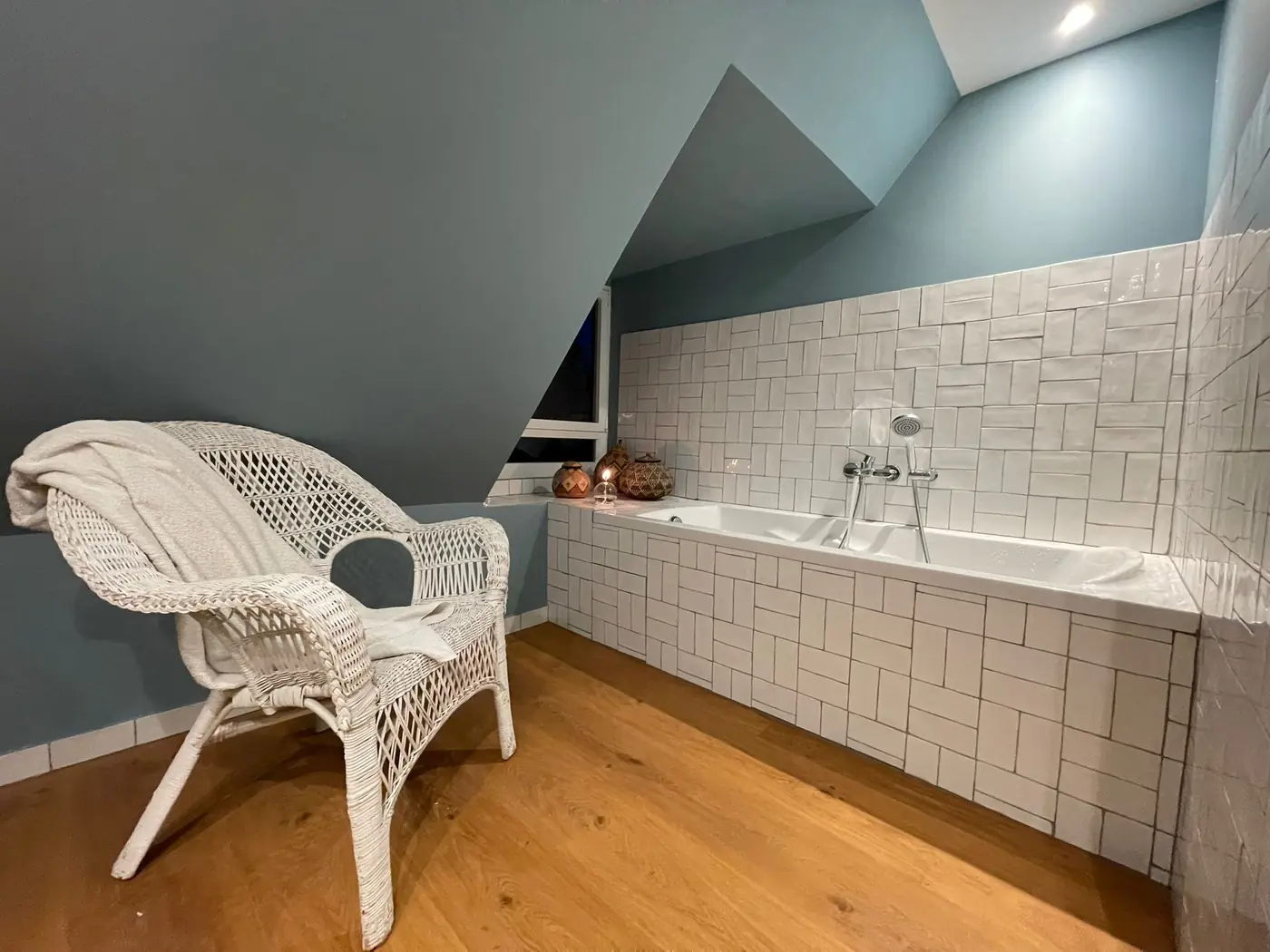 Salle de bains sous combles avec baignoire carrelée et parquet chêne
