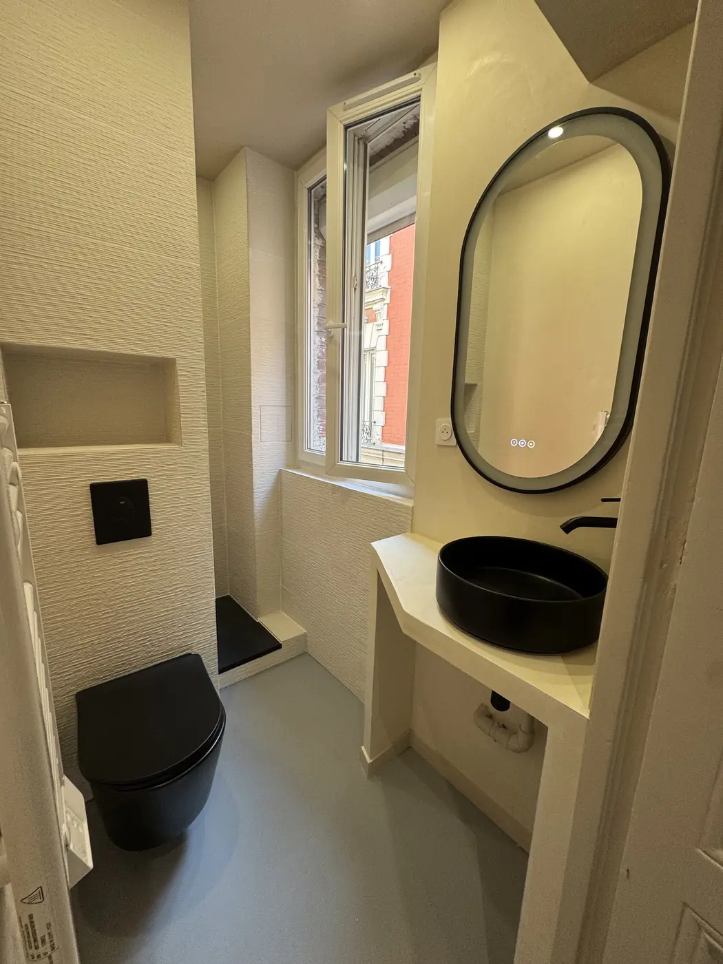 Salle d'eau avec miroir ovale, vasque noire et niche