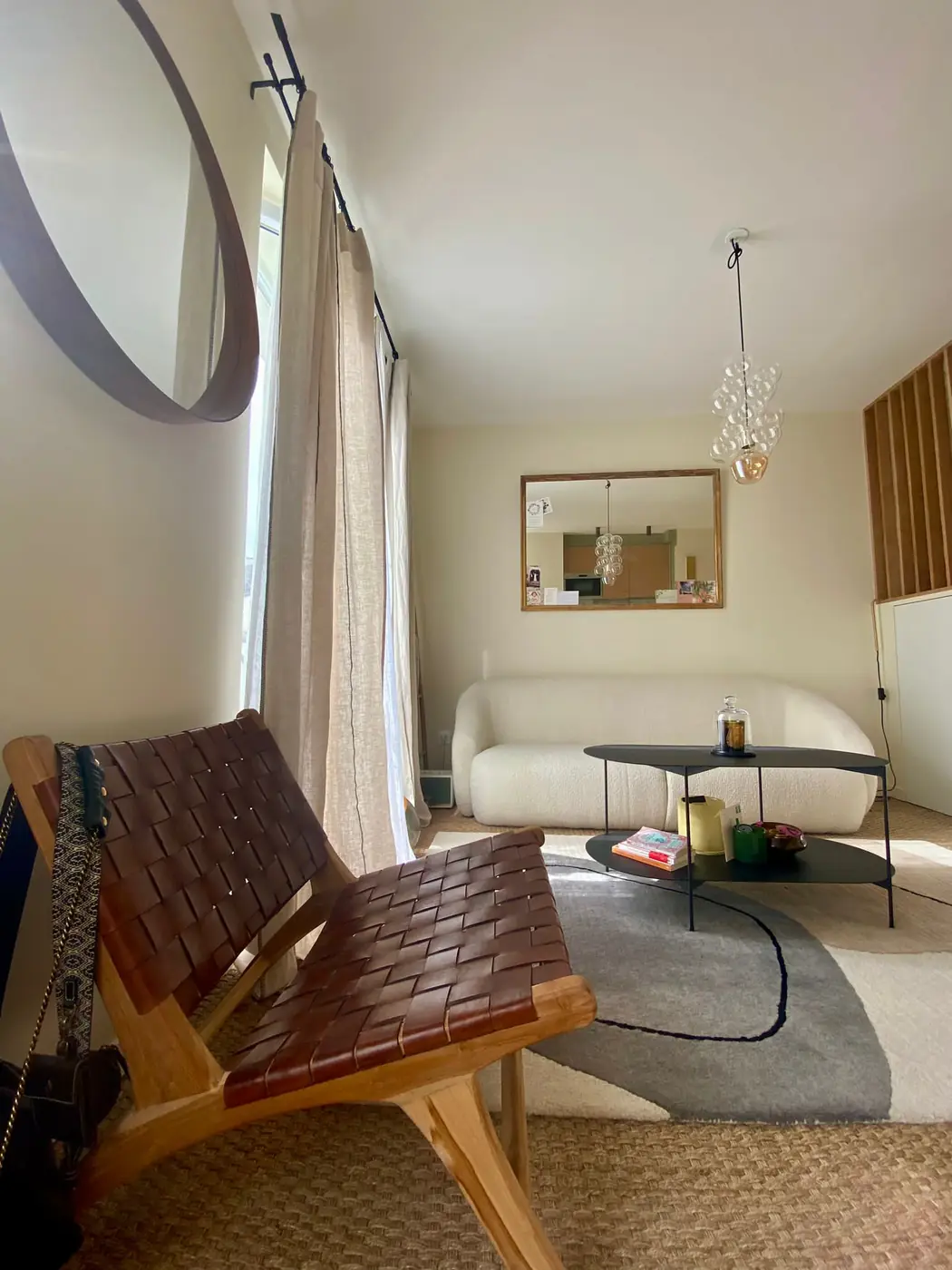 Séjour du studio avec fauteuil cuir et tapis, claustra en bois