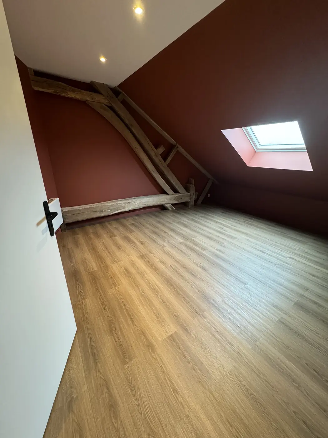 Chambre sous combles aux murs terracotta et charpente apparente dans une longère en Sologne
