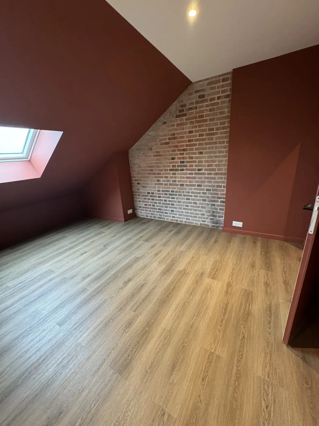 Chambre mansardée avec mur de brique et fenêtre de toit
